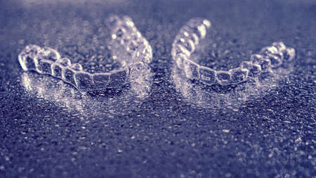 Blue aligners, tooth retainers lie on glass with water droplets