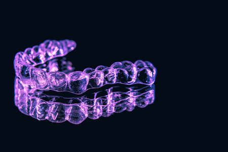 Transparent aligners, tooth retainers lie on glass with water droplets on a black backgroundの写真素材