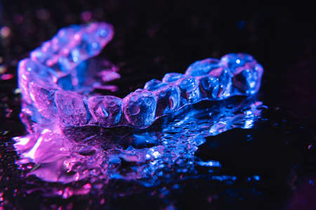 Transparent aligners, tooth retainers lie on glass with water droplets on a black backgroundの写真素材