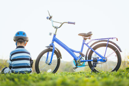 Child in helmet and protection sits near his bikeの写真素材