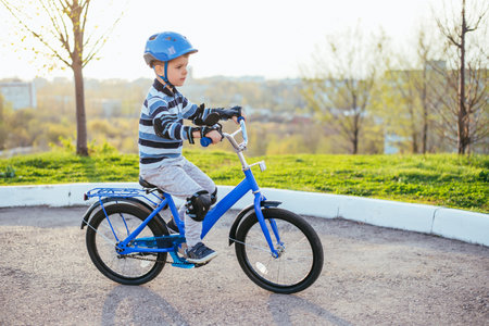 A child in a helmet and protection rides a bicycle on the roadの写真素材