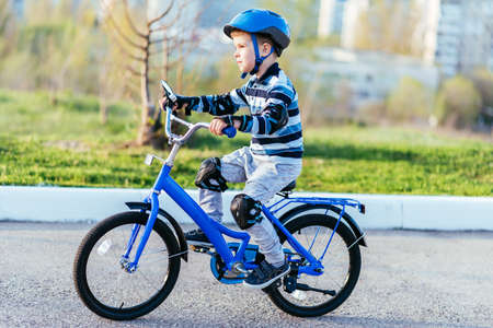 A child in a helmet and protection rides a bicycle on the road