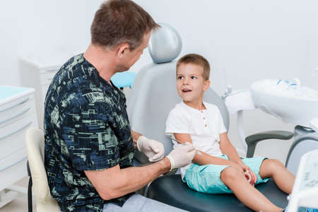 Doctor orthodontist tells the child how to care for teeth and maintain hygieneの写真素材
