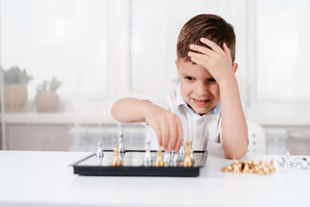 A 5 year old child plays chess by himself in his room at homeの写真素材