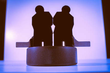 Black figures of two hockey players and one puck on a blue background.