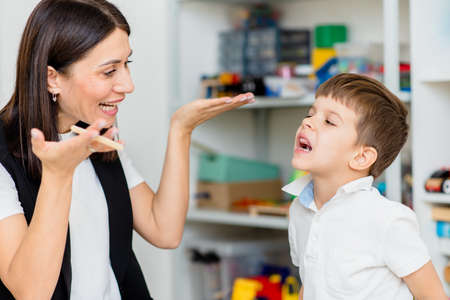 A woman speech therapist deals with the child and teaches him the correct pronunciation and competent speech.の写真素材