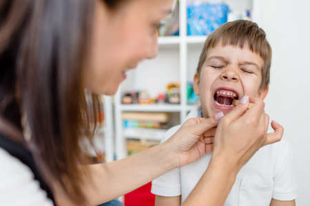 A little preschool boy is engaged in a speech therapist office and corrects his speech