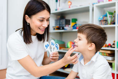 A cute child with a speech therapist is taught to pronounce the letters, words and sounds correctly.の写真素材