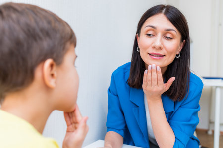Woman speech therapist helps a child correct the violation of his speech in her officeの写真素材
