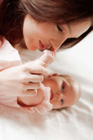 Portrait of a young woman kissing her little baby daughter