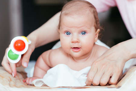 Portrait of a beautiful baby girl lies on a white sheet in her room