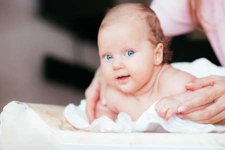 Portrait of a beautiful baby girl lies on a white sheet in her room