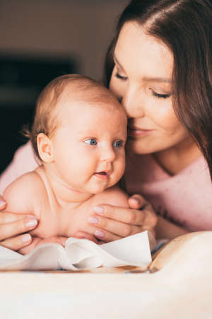 Portrait of a young woman kissing her little baby daughterの写真素材