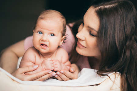 Portrait of a young mother who tenderly takes care of her baby girlの写真素材