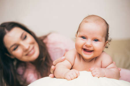 Happy laughing baby spending time with his mom in the apartment