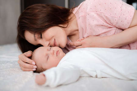 Mother takes care of her sleeping baby daughter in the bedroom
