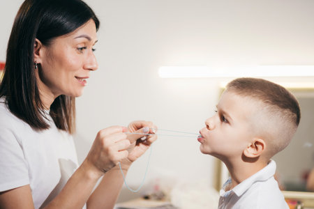 Woman speech therapist helps a child correct the violation of his speech in her officeの写真素材