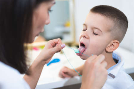 Woman speech therapist helps a child correct the violation of his speech in her officeの写真素材
