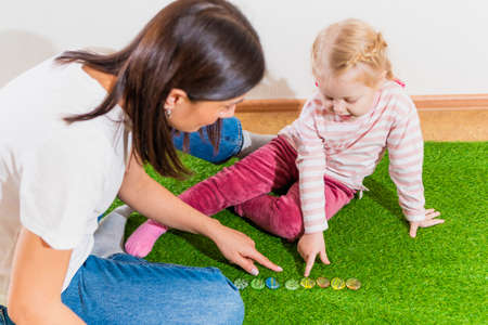 Woman speech therapist helps little girl to correct her speech in her office