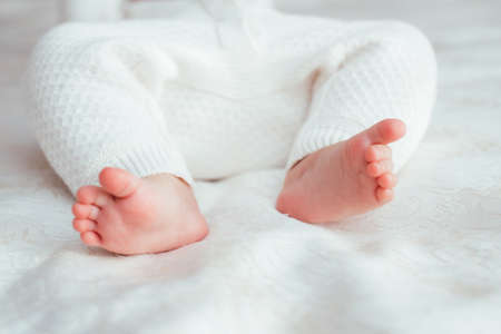 Bare baby legs on the bed in the room close-upの写真素材