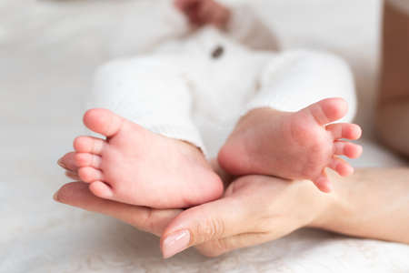 A woman touches her baby's feet with her handsの写真素材
