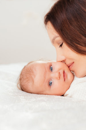 Beautiful mother kissing her little baby daughter