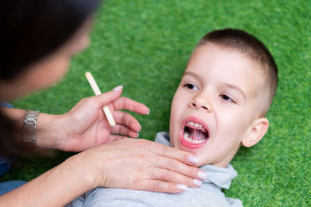 Woman speech therapist helps a child correct the violation of his speech in her office