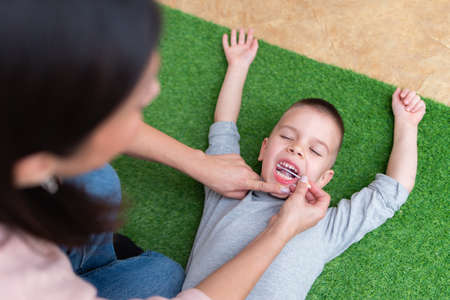 Woman speech therapist helps a boy correct the violation of his speech