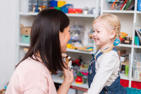 Woman speech therapist helps cute girl to learn correct pronunciation and competent speech in her officeの写真素材