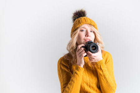 Portrait of a cute girl photographer in a knitted hat who takes pictures in the studioの写真素材
