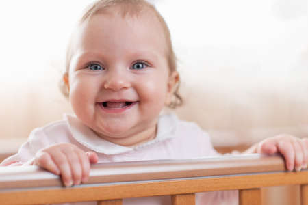 Portrait of a happy and laughing toddler girl in a cribの写真素材