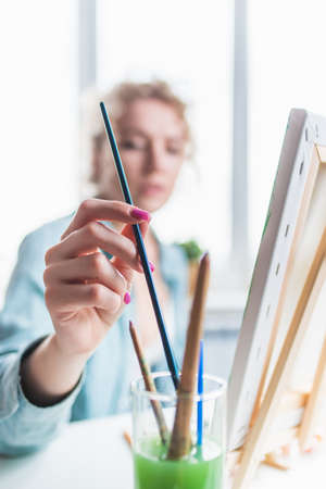 Beautiful girl artist paints a picture at homeの写真素材
