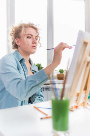 Beautiful girl artist paints a picture at home