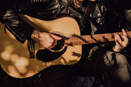 Man playing acoustic guitar in nature on a sunny day