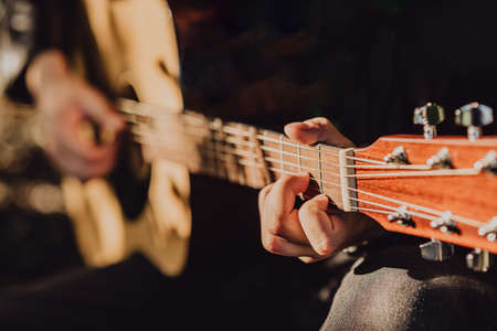 A man plays an acoustic guitar and jams chords close-up in natureの写真素材