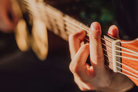 A man plays an acoustic guitar and jams chords close-up in natureの写真素材