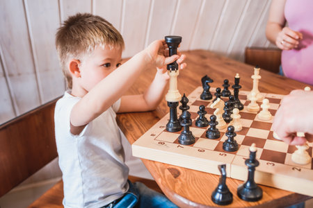 Boy playing chess at home at the tableの写真素材