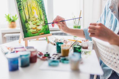 Beautiful girl artist paints a picture at homeの写真素材