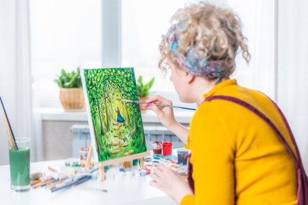 Beautiful girl artist paints a picture at homeの写真素材