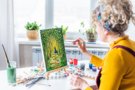 Beautiful girl artist paints a picture at homeの写真素材