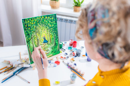 Beautiful girl artist paints a picture at homeの写真素材