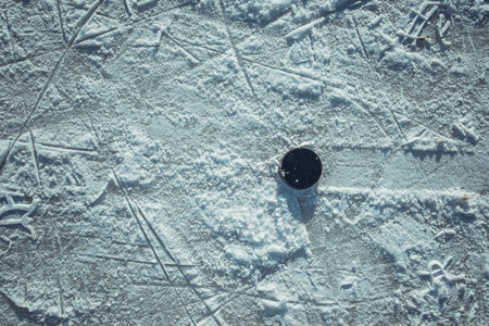 black hockey puck lies on ice at stadiumの写真素材