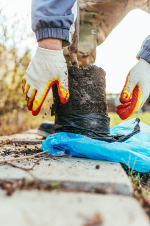 A man plants a young fruit tree in the village. The farmer unpacks a new seedling and puts it in the ground. The concept of environmental protection and ecologyの写真素材