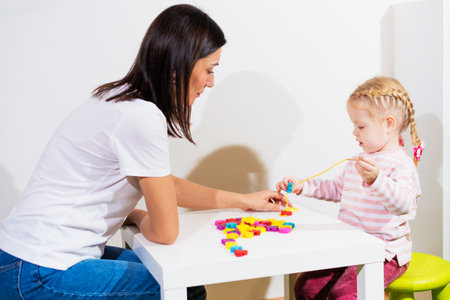 Woman speech therapist helps cute girl to learn correct pronunciation and competent speech in her officeの写真素材