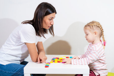 Woman speech therapist helps cute girl to learn correct pronunciation and competent speech in her...