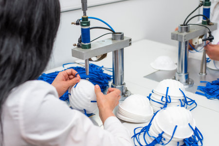 A woman works in a factory for the manufacture of medical masks with nanofibre and solder loops with ultrasound on a machine. Coronavirus and Covid-19 Protection. close-upの写真素材