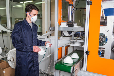 The guy works in a factory for the manufacture of medical masks with nanofiber. Coronavirus and Covid-19 Protectionの写真素材