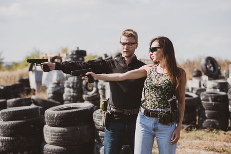 Shooting instructor teaching a woman how to properly handle a weapon at the shooting rangeの写真素材