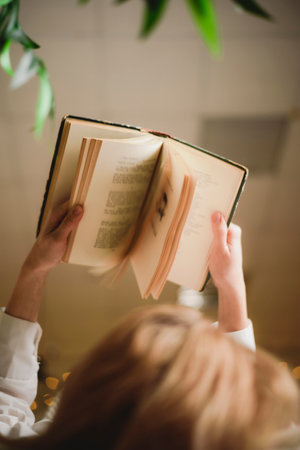 Girl reading a book lying on the bed at home before bedの写真素材
