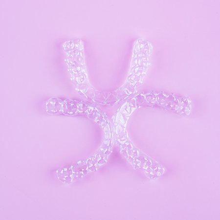 Invisible aligner teeth retainers on a pink background